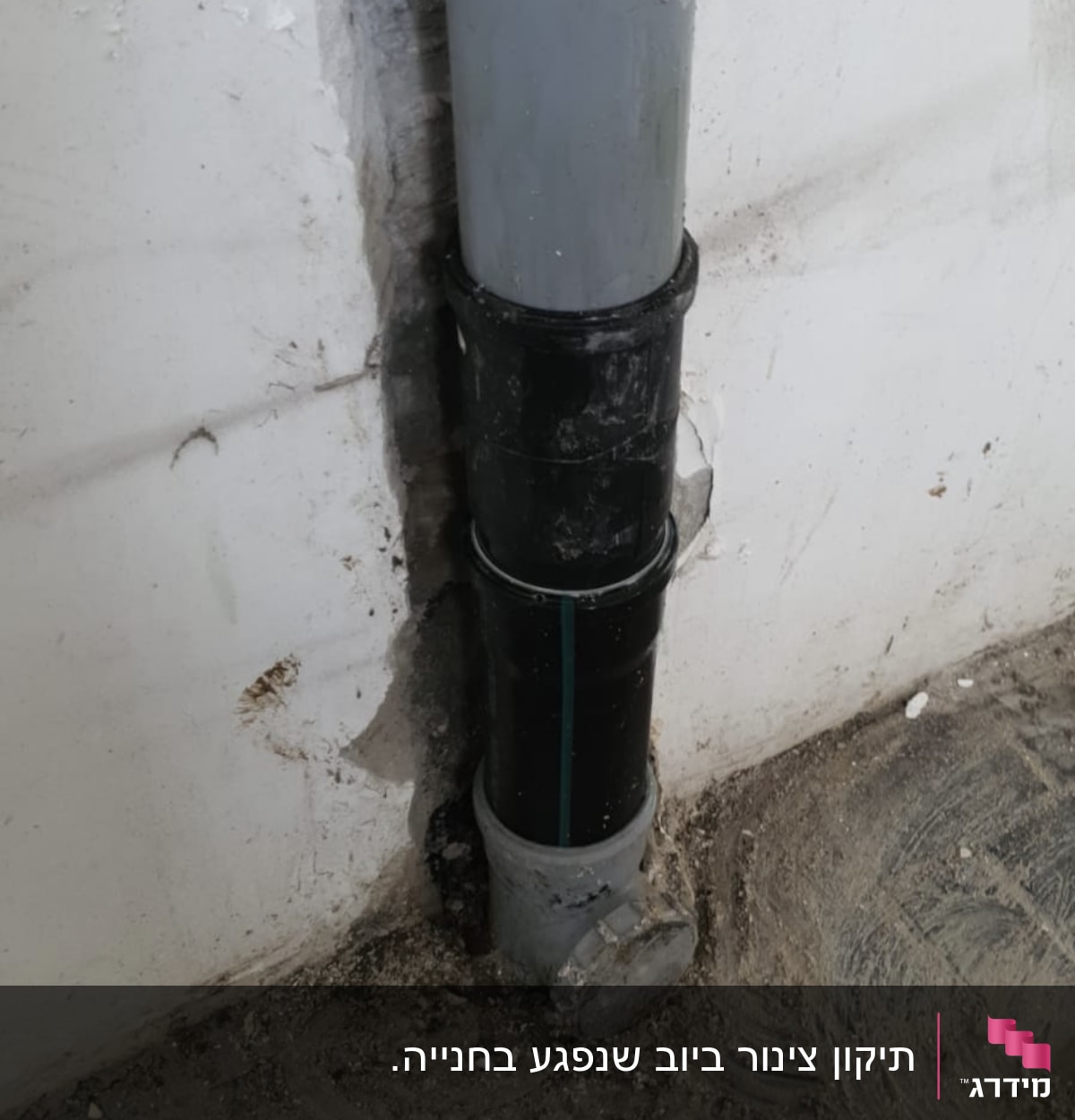 צינור ביוב מותקן בקיר עם טיח מתקלף